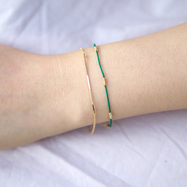 Wrist wearing green silk bracelet with gold wire