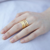 Hand wearing yellow gold lace ring with other rings
